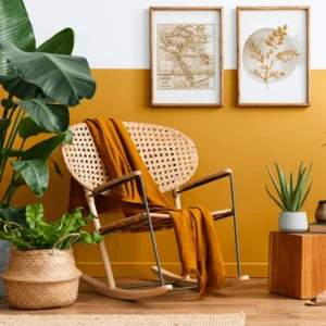 Ambiente interno de casa com cadeira de balanço, alguns vasos de planta e quadros decorativos